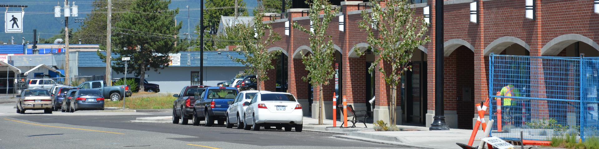 A row of cars park on a street adjacent the Haney Place Mall Bus loop.
