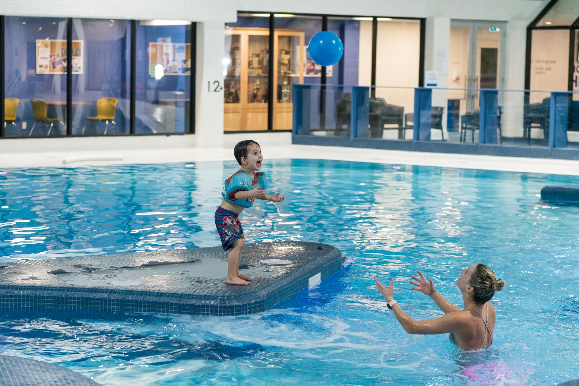 child and a mom playing in indoor swimming pool