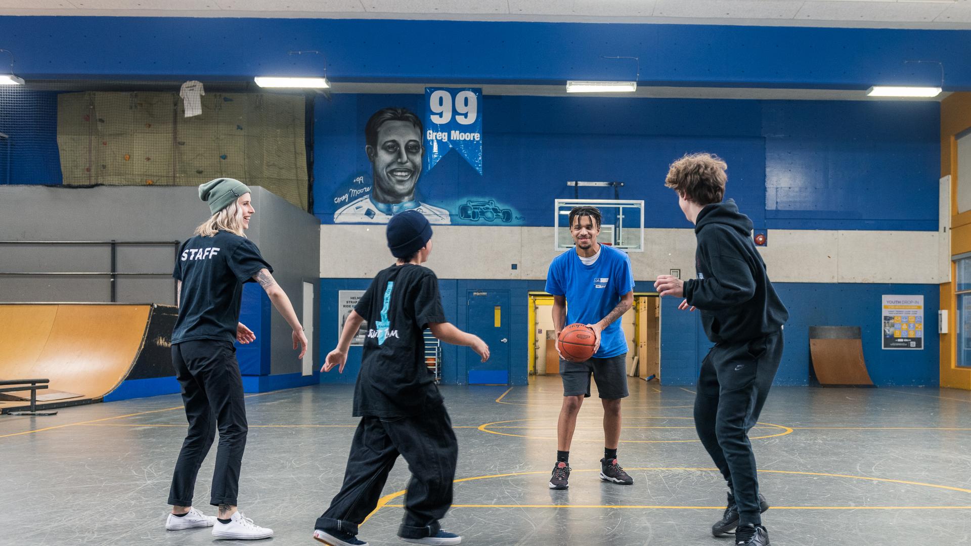 Two boys play basketball with two Maple Ridge staff in the Greg Moore Youth Centre.