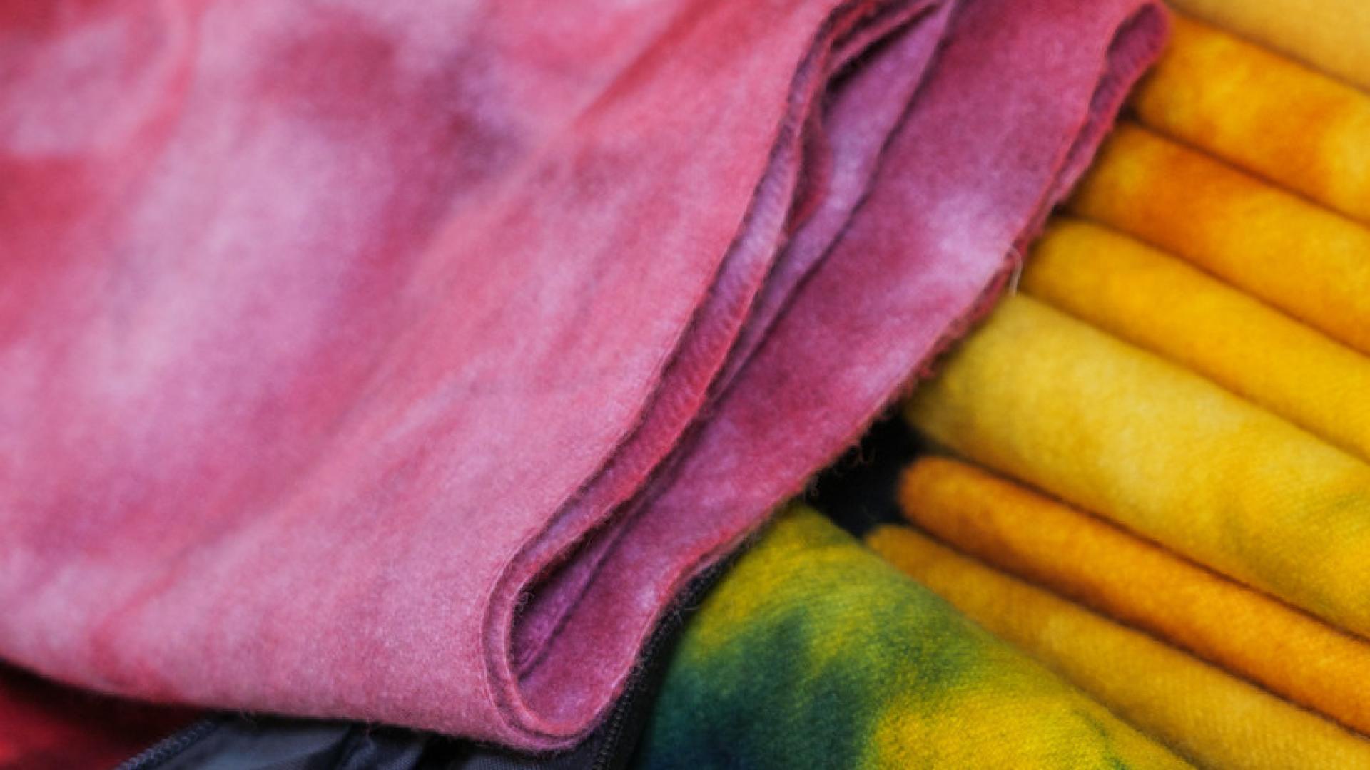 Colourful dyed fabrics in pink, yellow, and green.