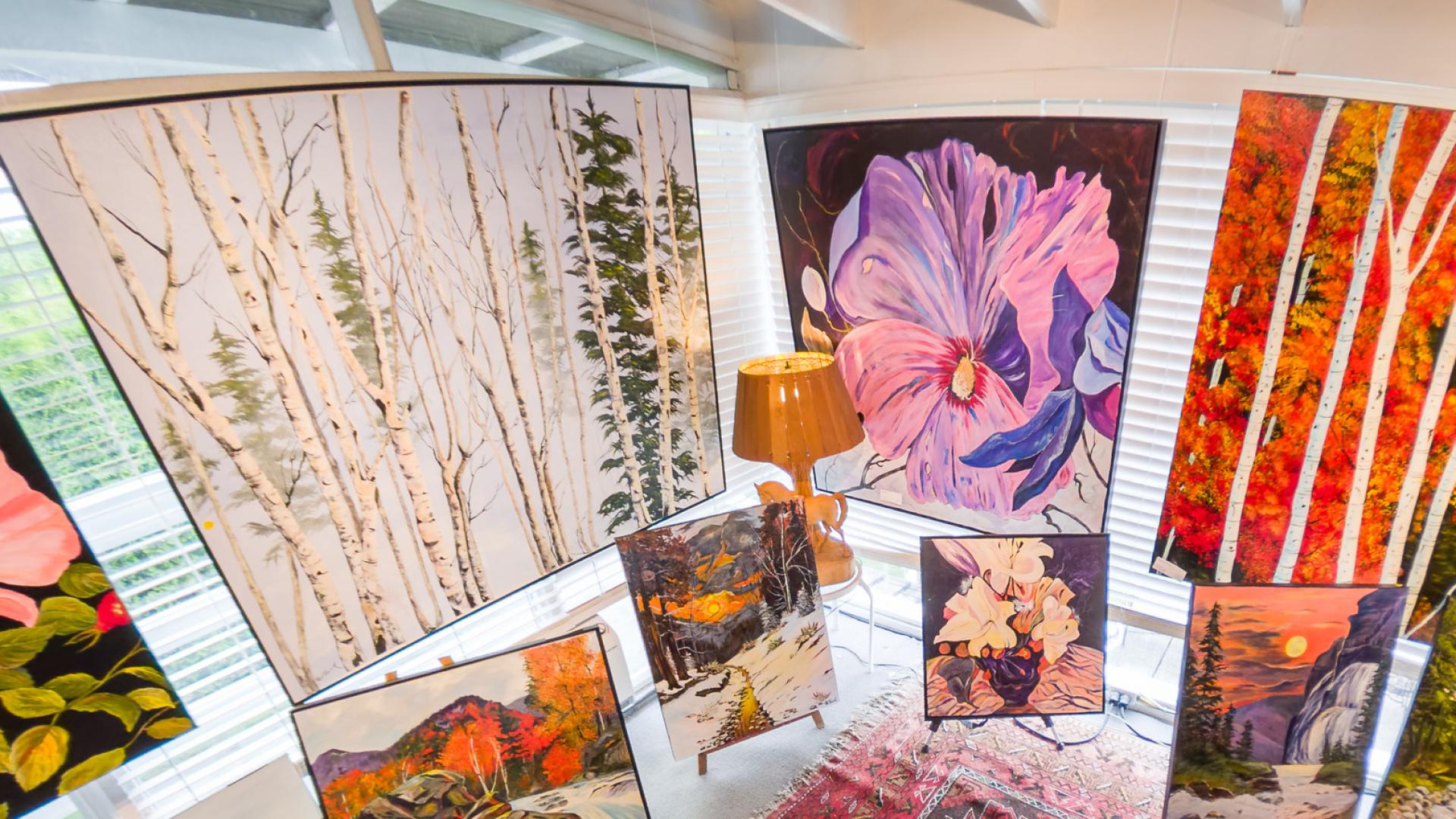 A corner display showcasing various painted artworks of differing sizes.