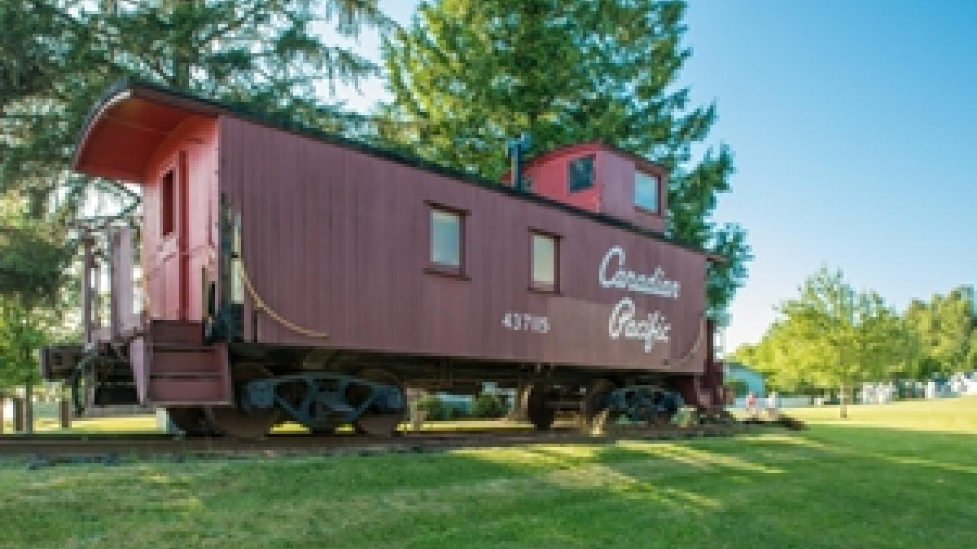 Old wooden caboose with the words Canadian Pacific on its side on display on a small segment of rail.