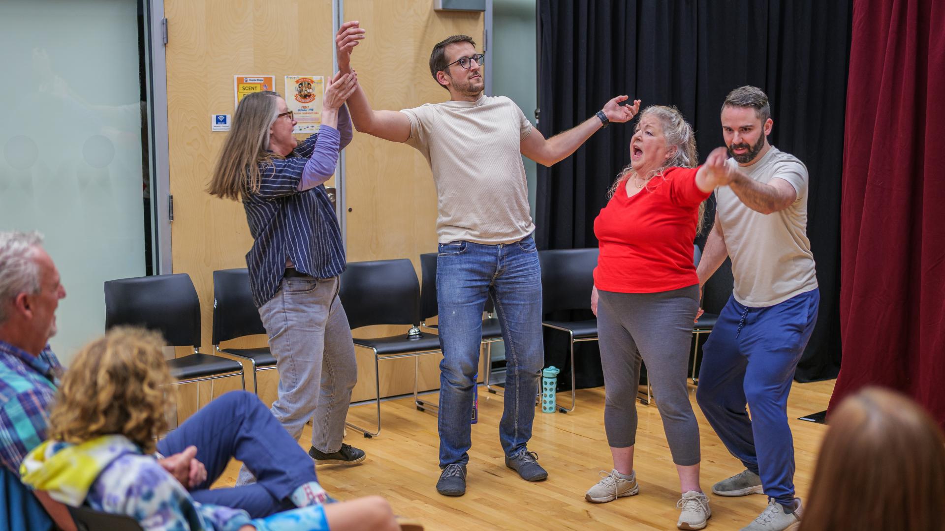 Participants watch as other students act out an improvisational scene in the middle of the Albion Community Centre.