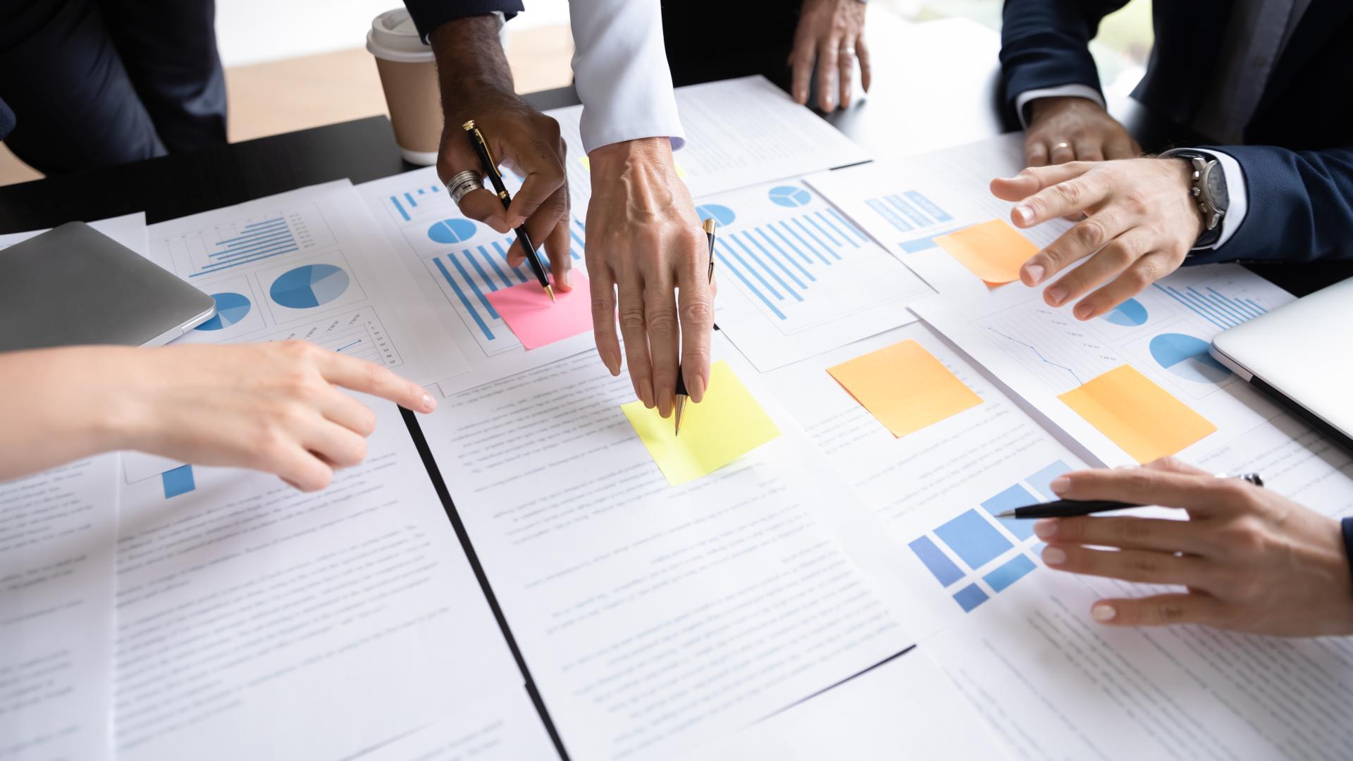A group of people collaborate by placing sticky notes onto a whiteboard table.