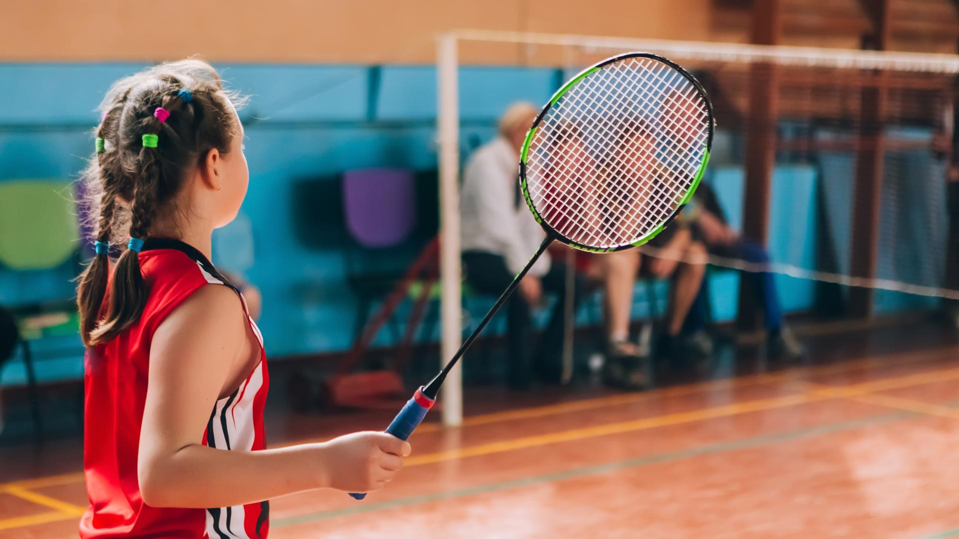 Young Girl Playing Badminton in Gymnasium