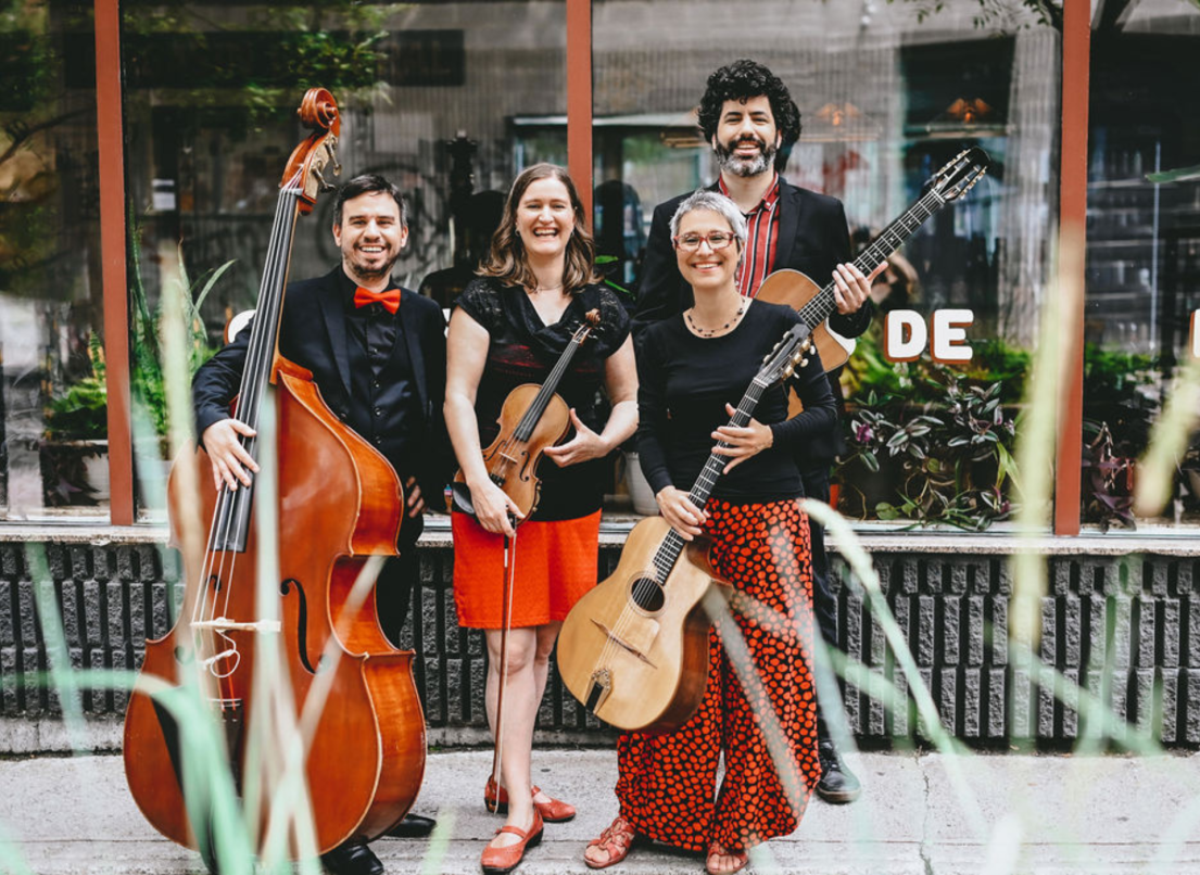 Christine Tassan et Les Imposteurs pose in from of a store with their various stringed instruments, including a guitar, violin and cello. 
